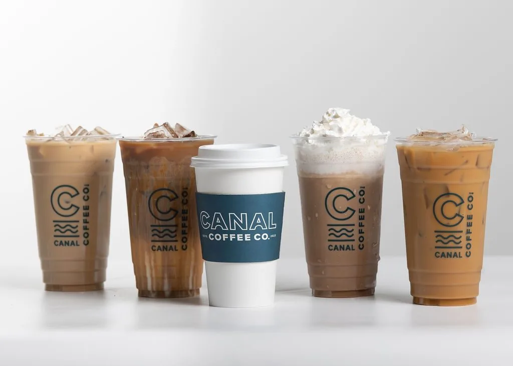 A white hot coffee cup and four iced coffee drinks, one with whipped cream, from Canal Coffee Co.