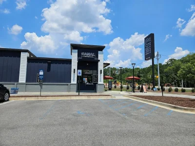 Canal Coffee storefront seen from the parking lot with the blue sky and white clouds in the background.