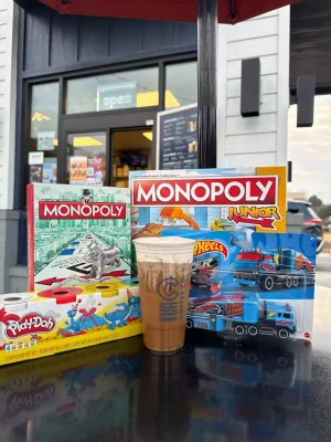 Canal Coffee cold brew displayed with Monopoly, Monopoly Junior, Play-Doh, and Hot Wheels toy donations.
