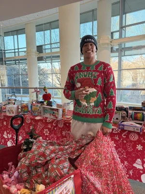 Jalen Coker with donated toys and wrapped gifts at a holiday charity event.