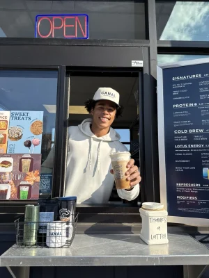 Jalen Coker at the Canal Coffee drive-thru window holding a cold brew drink.
