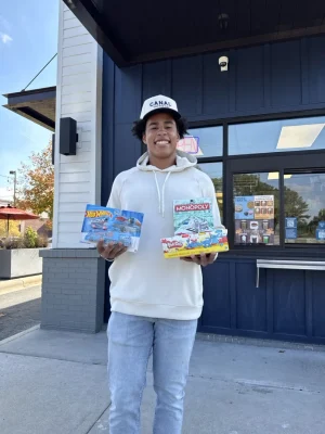 Jalen Coker outside Canal Coffee holding donated toys for a holiday charity drive.