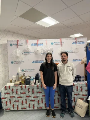 Two people standing in front of a Canal Coffee beverage station at an Atrium Health Levine Children’s event.
