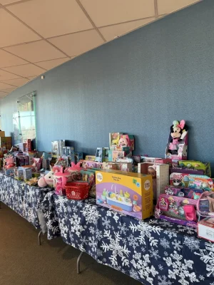 Tables filled with donated toys and gifts at a holiday charity event.