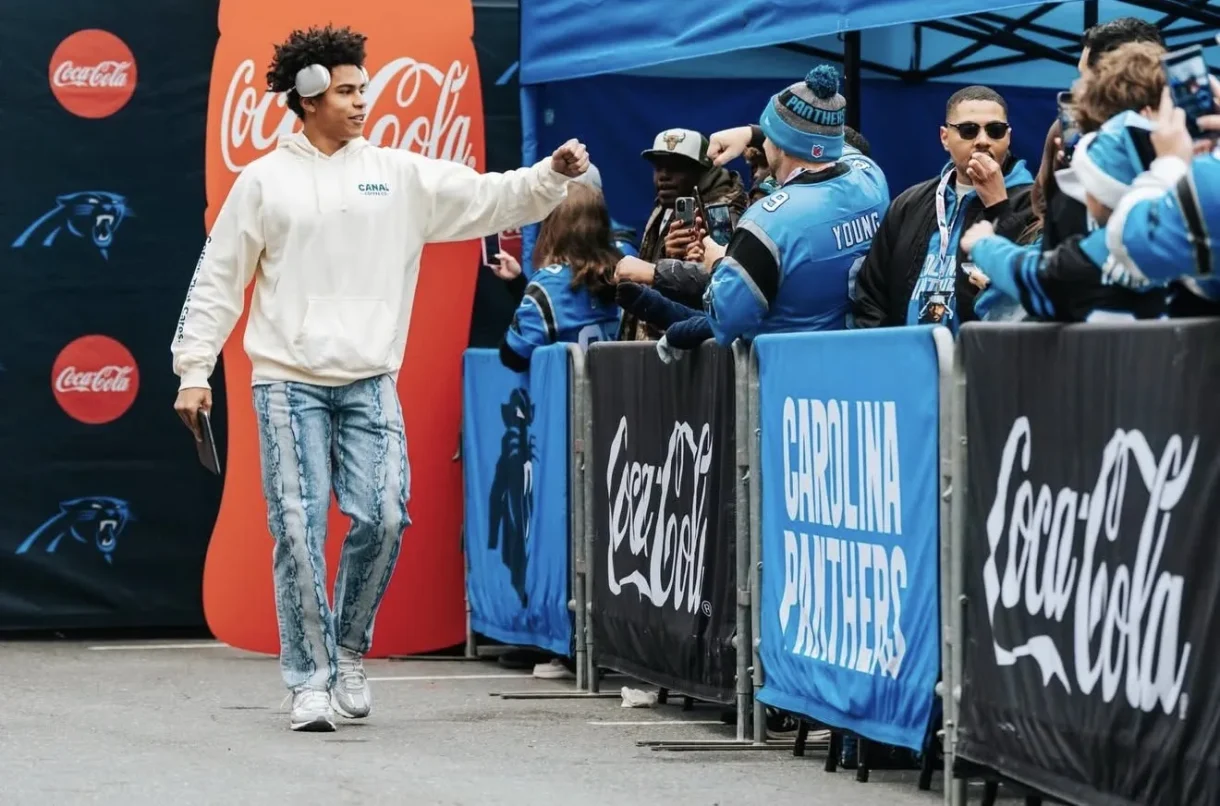 Jalen Coker greeting Carolina Panthers fans near Coca-Cola signage.