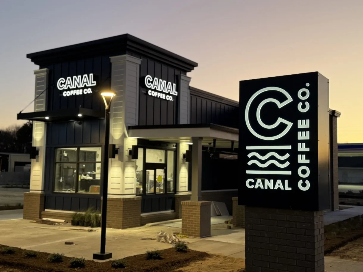 Canal Coffee Co. storefront and illuminated roadside sign at dusk.