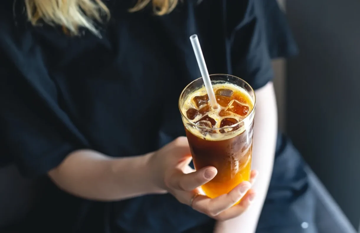 Person holding a glass of iced coffee with a straw