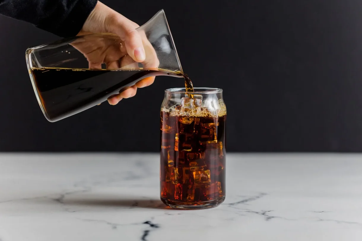 Cold brew coffee being poured into a glass over ice.